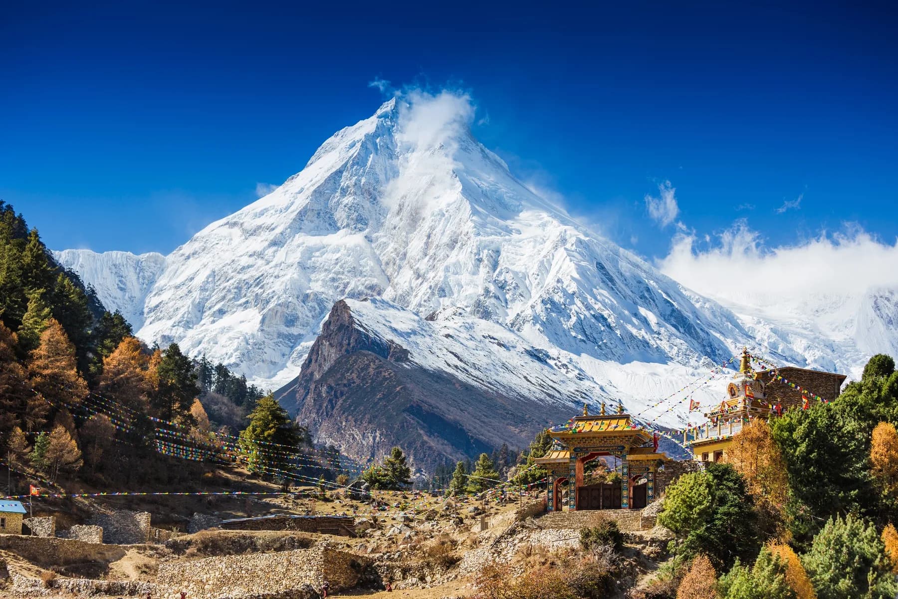 A stone-built mountain village below snow-capped peaks